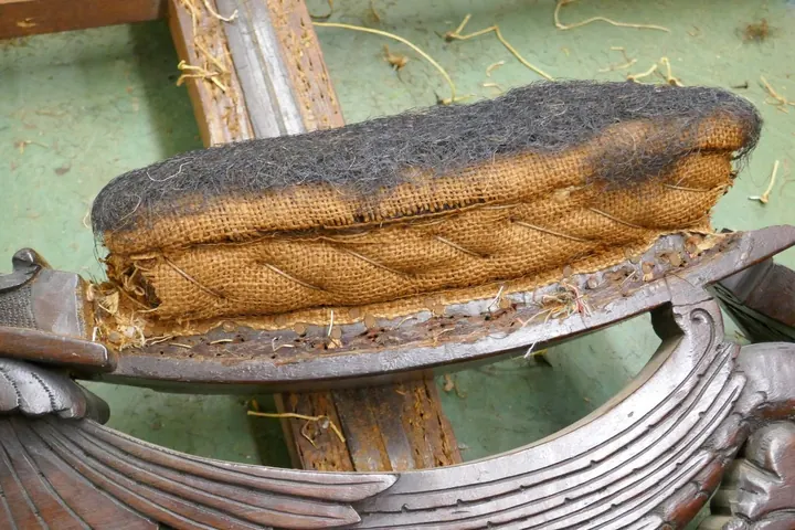 Multiple layers of horse hair and vegetable fiber are hand-sewn to cushion the arms.